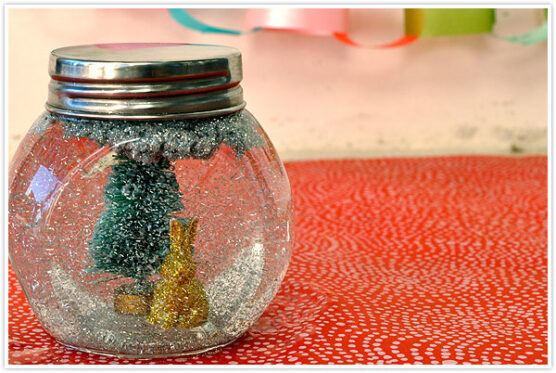 Tree and animal figurines with glitter inside a small glass jar