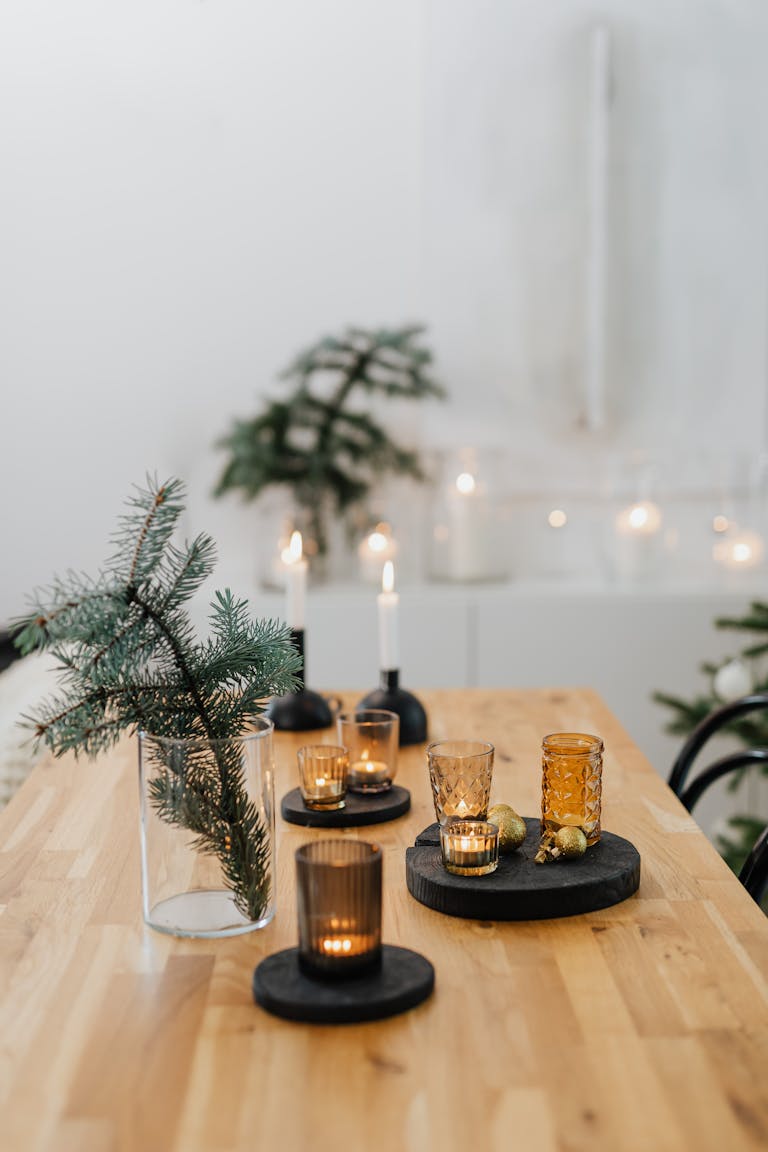 A festive table setting with candles and pine branches, perfect for a cozy Christmas celebration.
