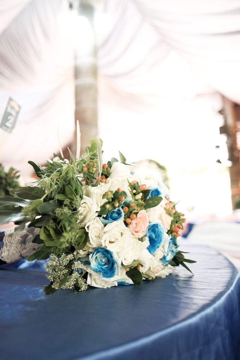 A sophisticated bridal bouquet featuring blue and white roses on a draped table, perfect for weddings.