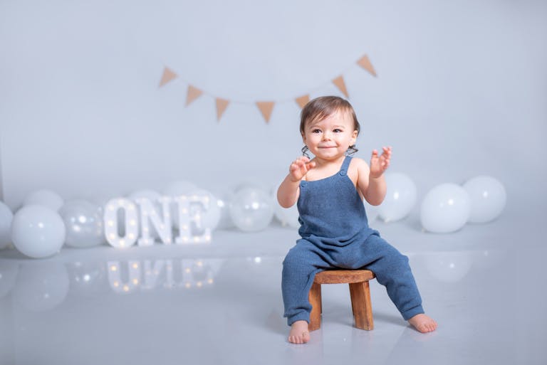 Charming baby boy celebrates first birthday with balloons and cute decor.