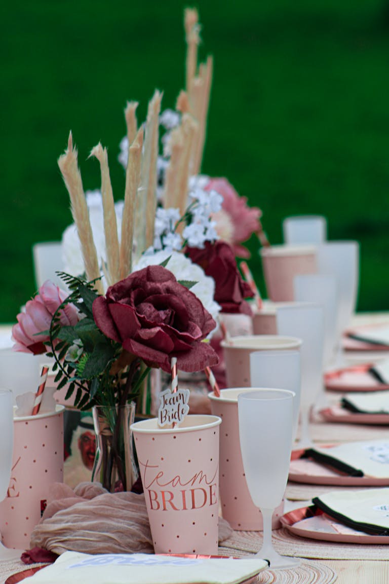 Chic bridal party table setting with roses and elegant cups.