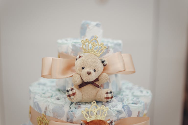 Delightful diaper cake adorned with a cute teddy bear and peach bow, perfect for baby showers.